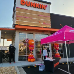 Grand opening balloon decorations with orange and pink balloon columns designed by a party decorator for Dunkin’ store event décor.