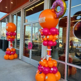 Grand opening balloon decorations with orange and pink balloon columns designed by a party decorator for Dunkin’ store event décor.