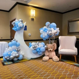 Blue, white, and gold balloon arch with teddy bear balloon decorations designed by a party decorator for an elegant baby shower party backdrop.