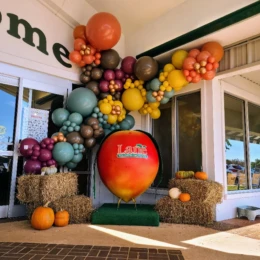 Fall balloon arch with earthy balloon decorations in orange, gold, and burgundy, styled by a party decorator for Lane Southern Orchards seasonal event décor.