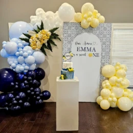 Custom balloon arch with navy, ivory, and pale yellow balloon decorations styled by a party decorator for a baby shower party backdrop.